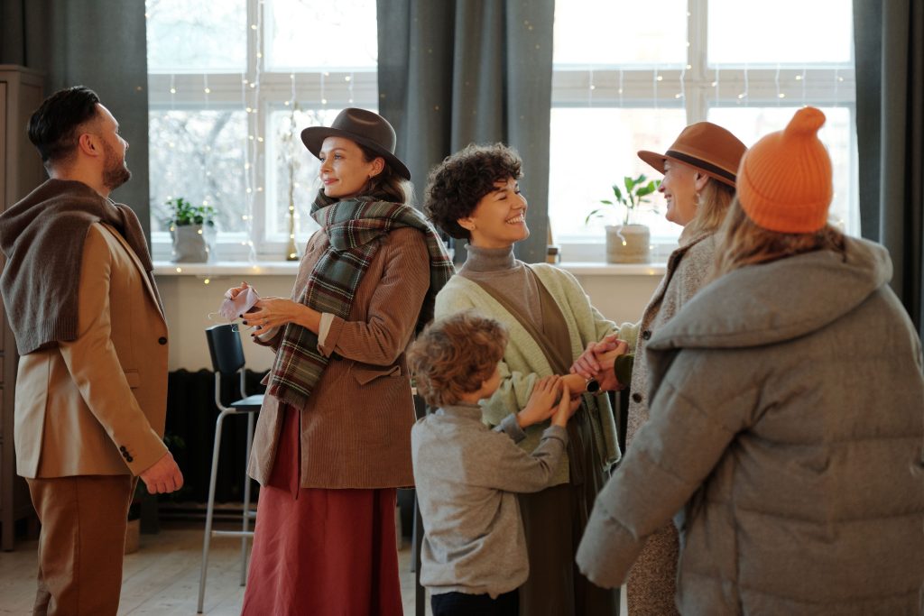 A diverse group of five adults and a child smiling and chatting in small groups, representing the joy of finding a supportive language community.