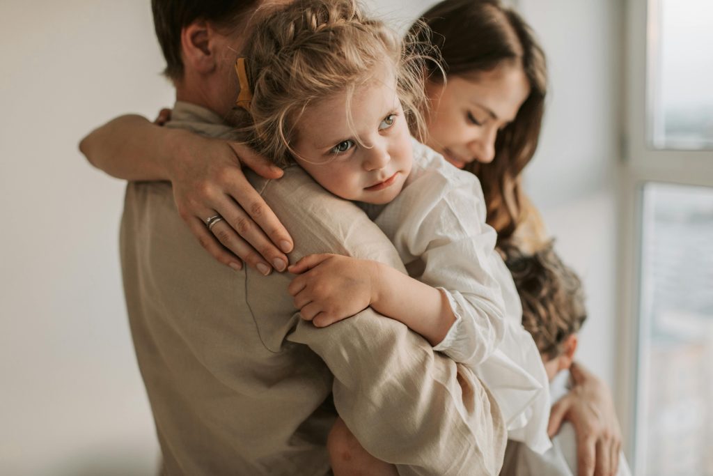 A mother and father hugging their two children tightly, illustrating the emotional journey and challenges of raising bilingual kids abroad.